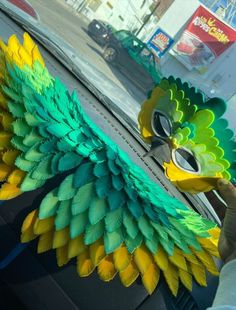 there is a fake bird in the back seat of a car that has been painted green, yellow and blue