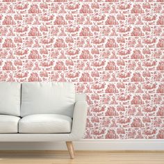 a white couch sitting in front of a wall with pink and white designs on it