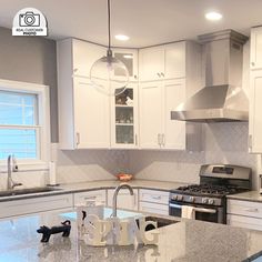 a kitchen with white cabinets and granite counter tops, stainless steel appliances and an island in the middle