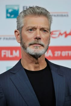 an older man with grey hair and beard wearing a suit