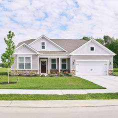 a large white house sitting in the middle of a lush green field on a sunny day