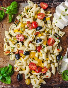 pasta salad with tomatoes, olives and mozzarella on a wooden cutting board