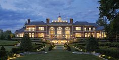 a large house with lots of windows and lights on it's front lawn at night