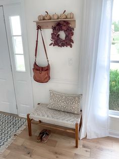 a wooden bench sitting in front of a window next to a wall mounted coat rack