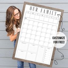 a woman holding up a large calendar with the words our family on it in front of her