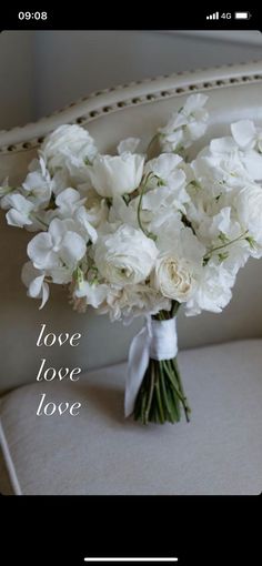 a bouquet of white flowers sitting on top of a chair with the words love in it