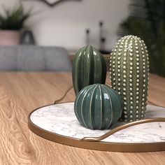 three ceramic cactus sitting on top of a white marble plate with gold trimmings