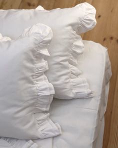 white pillows stacked on top of each other in front of a wooden floor and wall