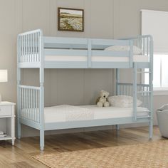 a blue bunk bed with two white pillows and a teddy bear sitting on the bottom bunk