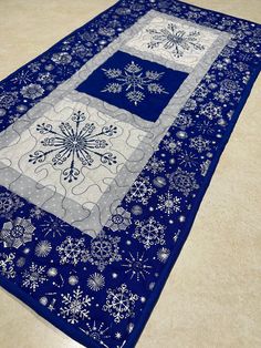 a blue and white table runner with snowflakes on the border is sitting on a tile floor