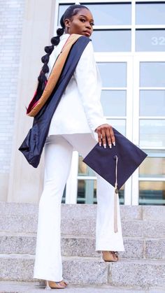 a woman in white pants and jacket carrying a black purse on steps outside a building