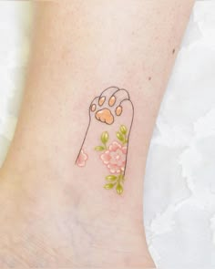 a small tattoo on the ankle of a woman's foot with a dog paw and flowers