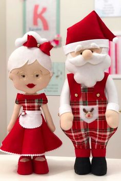 two dolls dressed in red and white are standing next to each other on a table