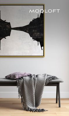 a black and white painting hanging on the wall next to a bench with two blankets