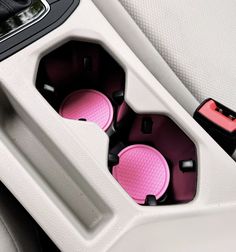 two pink buttons in the center console of a car with black trim and white interior