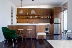 a kitchen with wooden cabinets and stools next to a counter top on a hard wood floor