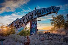 an old rusty sign sitting in the middle of nowhere