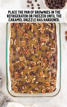 a brownie in a glass baking dish with pecans and chocolate chips on top