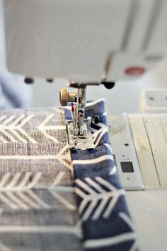 the sewing machine is on top of the blue and white fabric with an arrow pattern