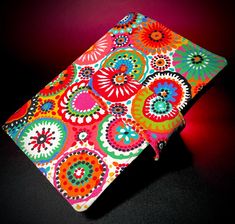 a multicolored notebook cover on a black surface with a red light behind it