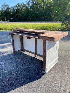 a desk made out of wood and white paint on the ground with trees in the background