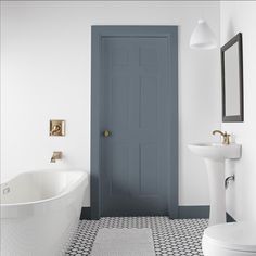 a white bathroom with a blue door next to a bathtub and sink in it