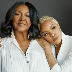 two women are posing for the camera with their arms around each other, one is wearing white