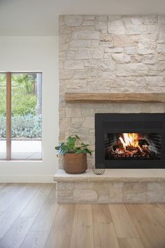 a living room with a fire place in the middle and wood floors on both sides