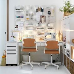 two office chairs sitting at a desk in front of a white wall