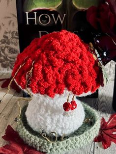 a crocheted red and white hat sitting on top of a table next to a book