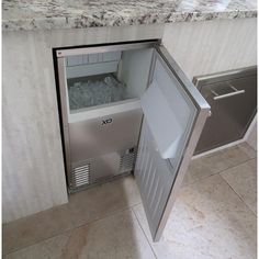 an open refrigerator with ice in it sitting on the floor next to a counter top