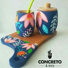 two vases with flowers painted on them are sitting on a wooden tray next to each other