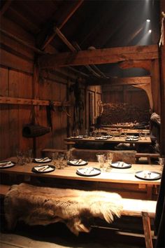 an old wooden table with plates and silverware on it in a room that has wood paneling