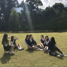 a group of young women sitting on top of a grass covered field next to each other