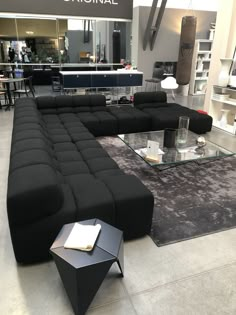 a large black couch sitting on top of a floor next to a glass coffee table