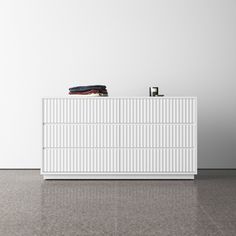 a white dresser sitting on top of a tiled floor next to a black and white wall