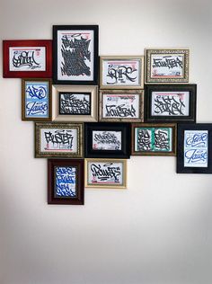 a bunch of framed pictures hanging on the wall with graffiti written all over them in different frames