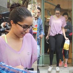 a woman in pink shirt and black leggings walking out of a building with other people