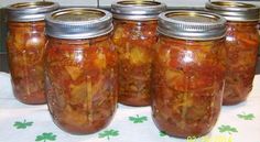 four jars filled with pickles sitting on top of a table