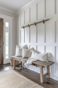 a wooden bench sitting in front of a door with white pillows on top of it