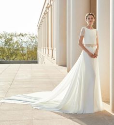 a woman standing in front of columns wearing a wedding dress