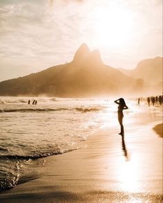 a woman standing on top of a beach next to the ocean