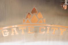 the gate city sign is painted gold and silver with an orange crown on it's top