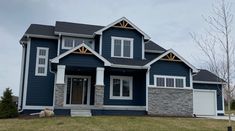 a blue house with white trim on the front and side windows, two car garages