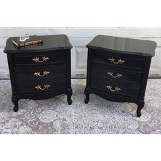 pair of black nightstands with gold trimming on the top and bottom, both side by side