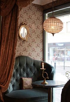 a chair sitting in front of a window next to a table with a candle on it