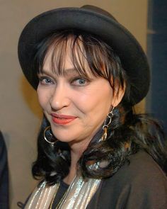 a woman wearing a black hat and silver dress with large hoop earrings on her ear