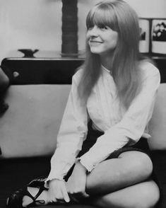 a black and white photo of a woman sitting on the floor with her legs crossed