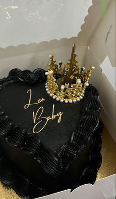 a black heart shaped cake with a tiara on top and the words i am baby written on it