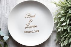 a white plate with the words, bad and lauren on it next to some greenery